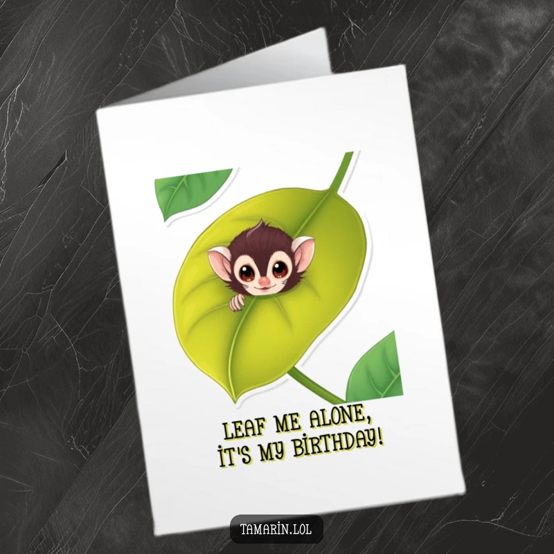 Funny Free Printable Tamarin Birthday Card: Adorable monkey peeking mischievously from behind a giant green leaf, ready for laughs.